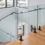 Frameless glass balustrade with black shoe support on stairs